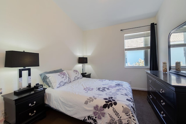 bedroom featuring baseboards and dark carpet