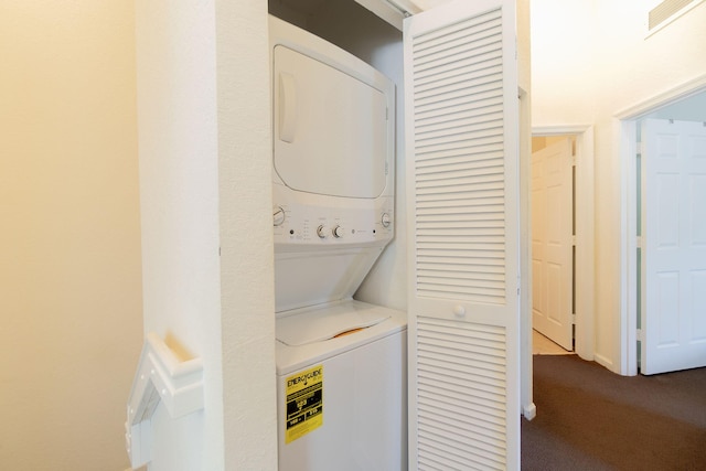 washroom with laundry area, dark carpet, stacked washer and clothes dryer, and visible vents