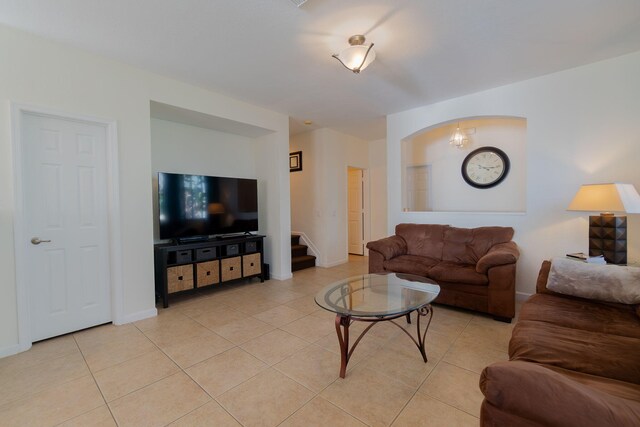 living area with light tile patterned flooring, stairway, and baseboards