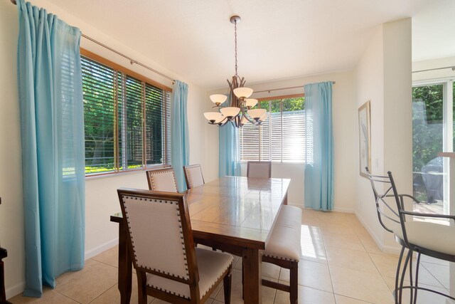 dining space featuring baseboards, a notable chandelier, and light tile patterned flooring