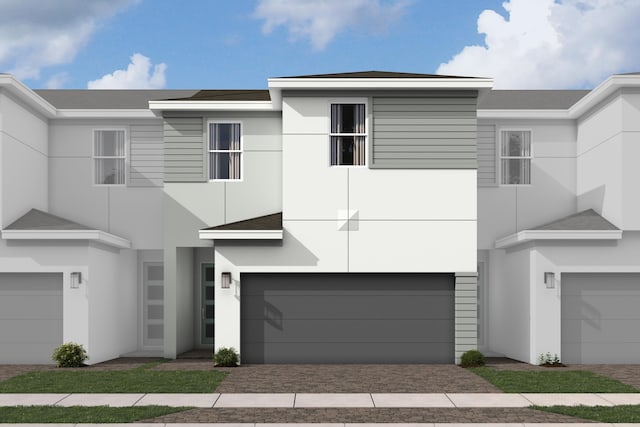 view of property featuring an attached garage, decorative driveway, and stucco siding