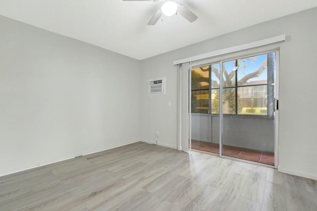 unfurnished room with a wall unit AC, wood finished floors, and a ceiling fan