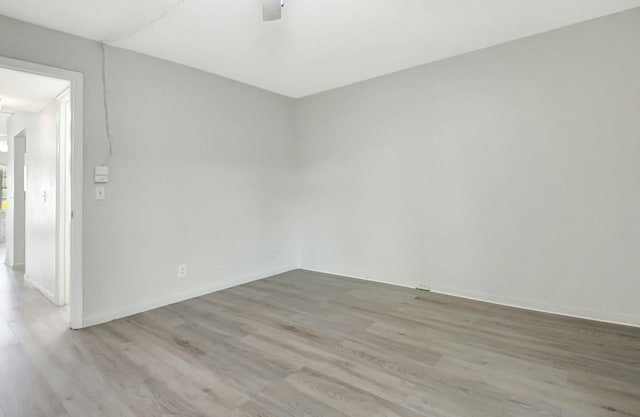 empty room featuring ceiling fan, baseboards, and wood finished floors