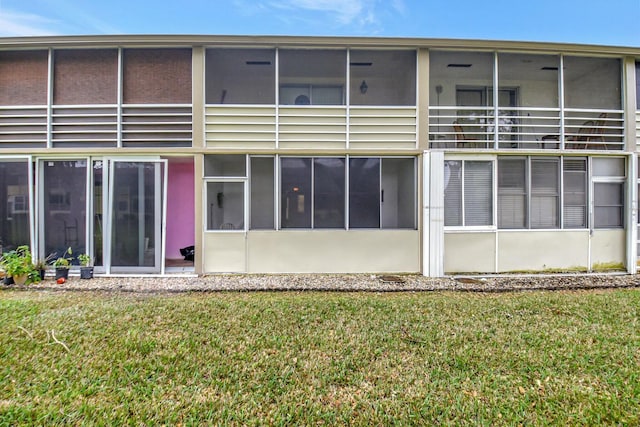 rear view of house featuring a sunroom and a yard