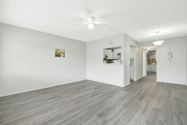 spare room featuring ceiling fan, baseboards, and wood finished floors