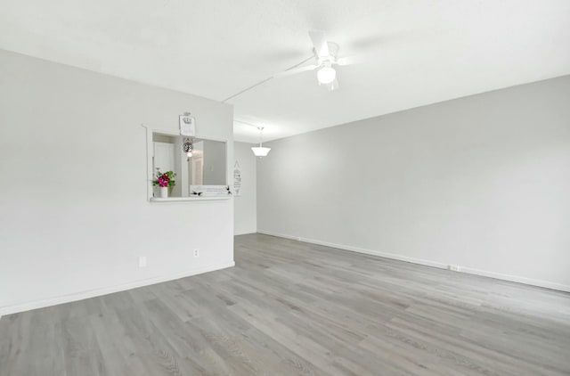 unfurnished room with ceiling fan, baseboards, and wood finished floors