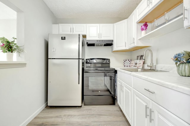 kitchen with electric range, white cabinets, a sink, and freestanding refrigerator