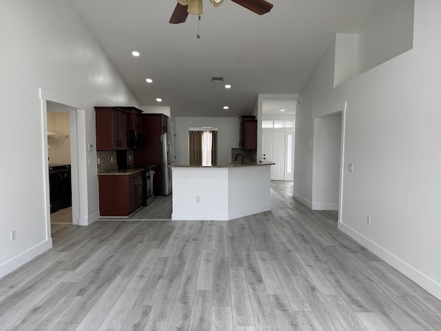 kitchen with light stone counters, stainless steel appliances, tasteful backsplash, light wood-style flooring, and open floor plan