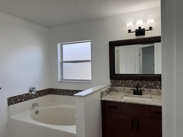 bathroom featuring a textured ceiling, backsplash, a bath, and vanity