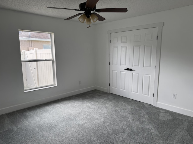 unfurnished bedroom with carpet floors, a closet, ceiling fan, a textured ceiling, and baseboards