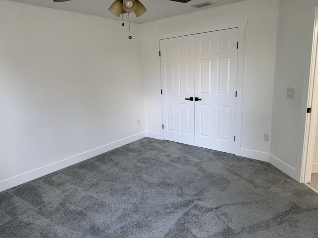 unfurnished bedroom featuring dark colored carpet, a closet, visible vents, and baseboards