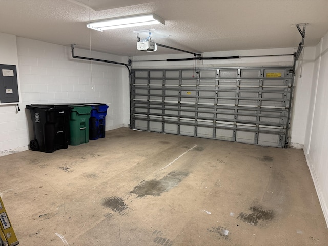 garage with concrete block wall, electric panel, and a garage door opener