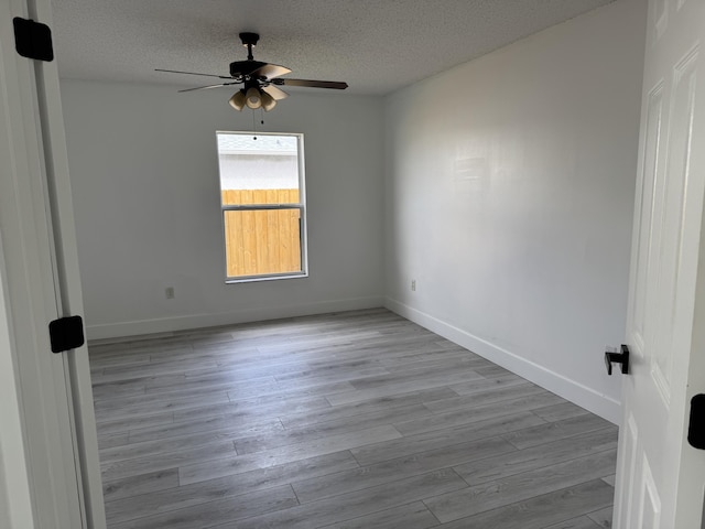 spare room with a ceiling fan, a textured ceiling, baseboards, and wood finished floors