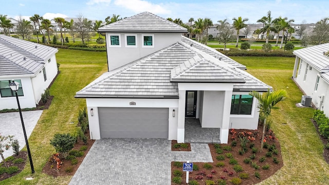 view of front facade featuring a garage, decorative driveway, central AC unit, and stucco siding