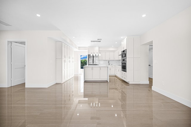 kitchen with baseboards, open floor plan, a center island, and white cabinetry