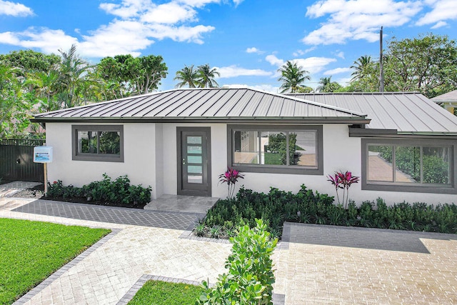 view of front facade featuring stucco siding, metal roof, and a standing seam roof