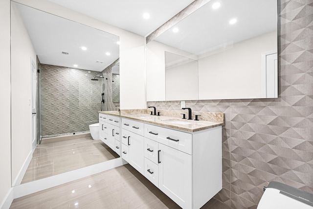 bathroom with toilet, a stall shower, tile walls, and a sink