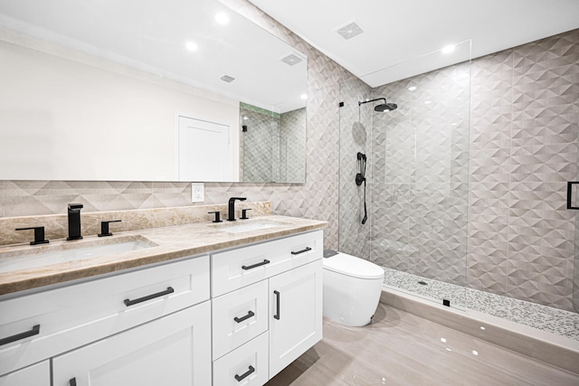 full bathroom featuring tile walls, tiled shower, double vanity, and a sink