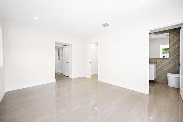 empty room with recessed lighting, visible vents, baseboards, and tile walls