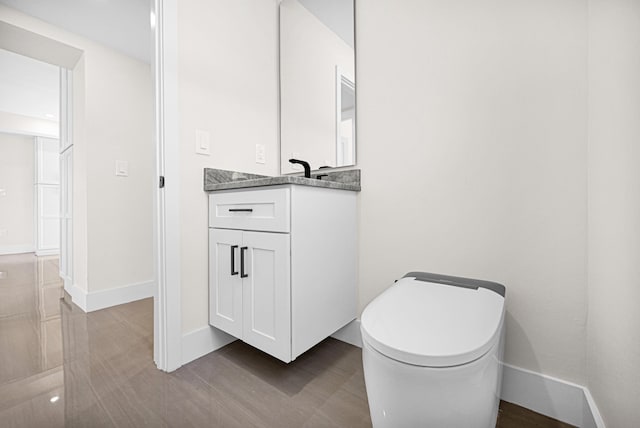 bathroom with baseboards, toilet, and vanity