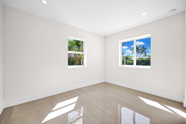 spare room with recessed lighting, a healthy amount of sunlight, and baseboards