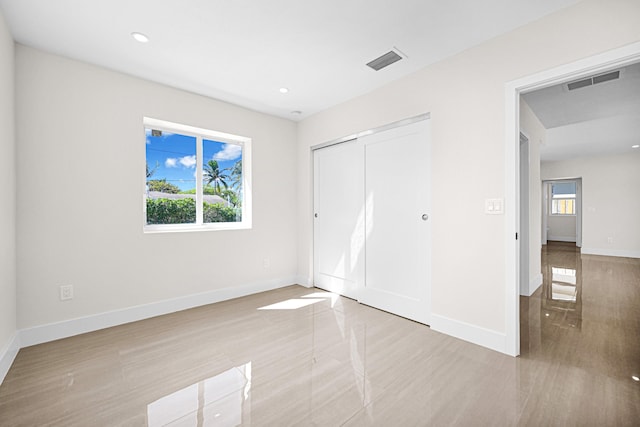 unfurnished bedroom with visible vents, multiple windows, and baseboards