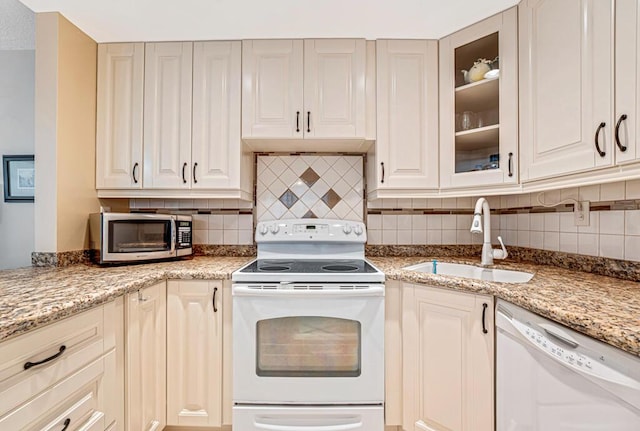 kitchen with white appliances, glass insert cabinets, backsplash, and a sink