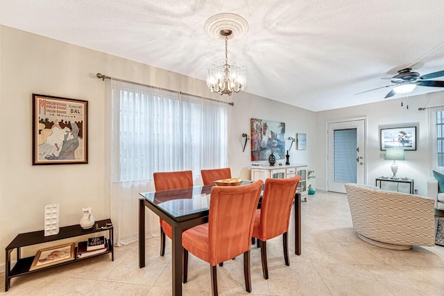 dining room featuring light tile patterned flooring, baseboards, a textured ceiling, and ceiling fan with notable chandelier