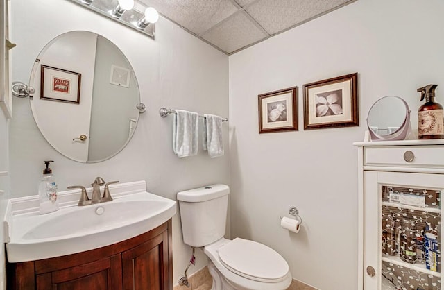 half bathroom featuring a paneled ceiling, vanity, and toilet