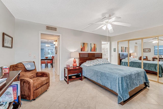 bedroom with ceiling fan with notable chandelier, a closet, visible vents, and light tile patterned floors