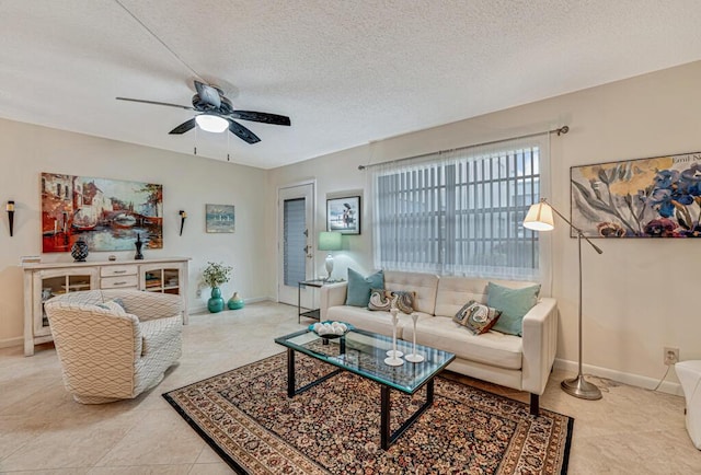 living room with light tile patterned flooring, ceiling fan, a textured ceiling, and baseboards