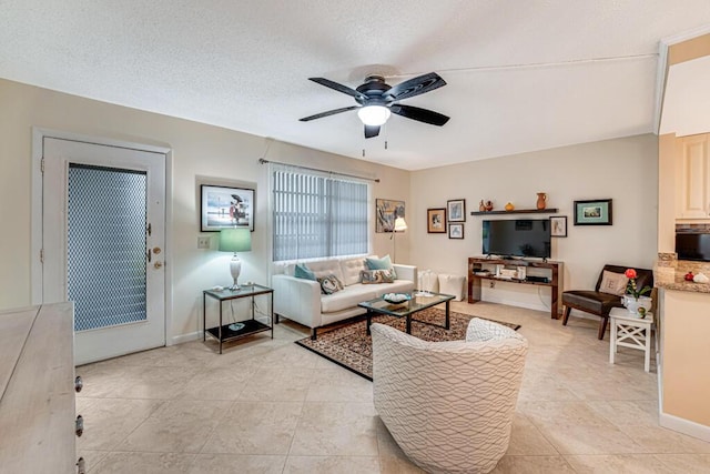 living room with light tile patterned floors, a textured ceiling, baseboards, and a ceiling fan