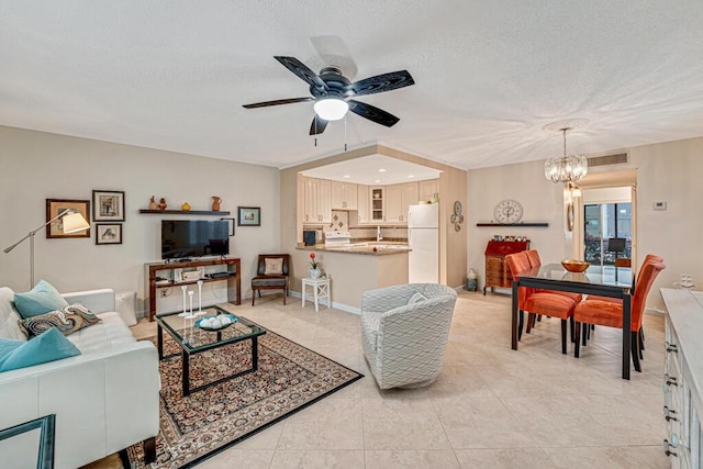 living area featuring light tile patterned floors, visible vents, baseboards, a textured ceiling, and ceiling fan with notable chandelier