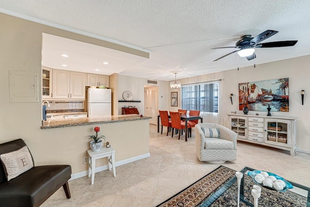 living area featuring light tile patterned floors, a textured ceiling, ceiling fan with notable chandelier, and baseboards