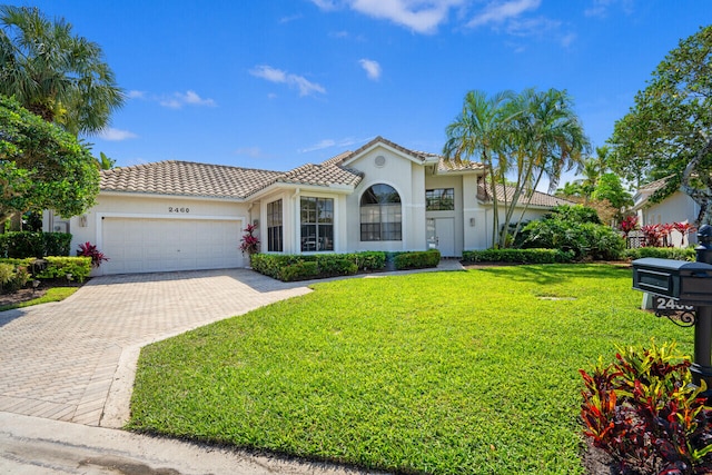 mediterranean / spanish-style home featuring a tiled roof, an attached garage, decorative driveway, a front lawn, and stucco siding