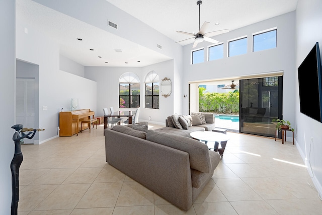 living area featuring a towering ceiling, visible vents, a ceiling fan, and light tile patterned flooring