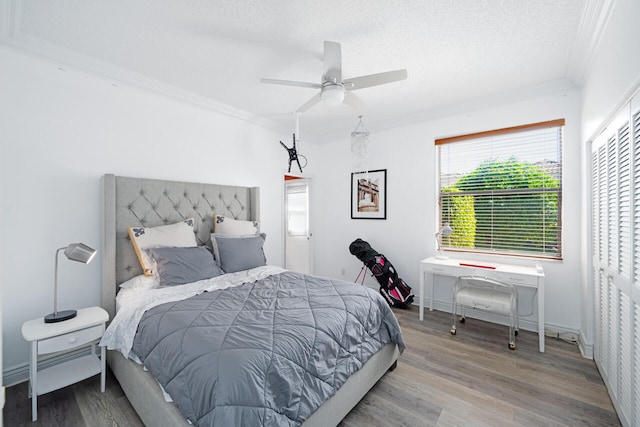 bedroom with ornamental molding, a textured ceiling, baseboards, and wood finished floors