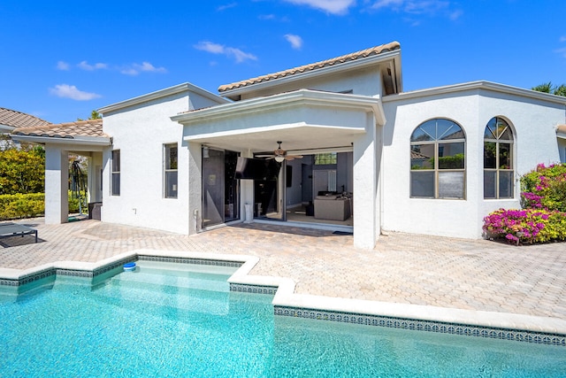 rear view of house featuring ceiling fan, a patio, a tile roof, an outdoor pool, and stucco siding