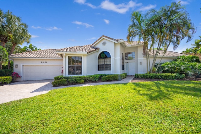 mediterranean / spanish-style home featuring an attached garage, driveway, a front yard, and stucco siding