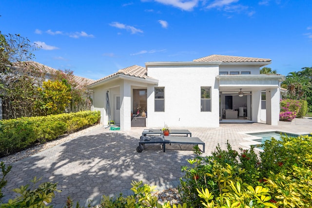 rear view of house featuring a tiled roof, a patio area, a ceiling fan, and stucco siding