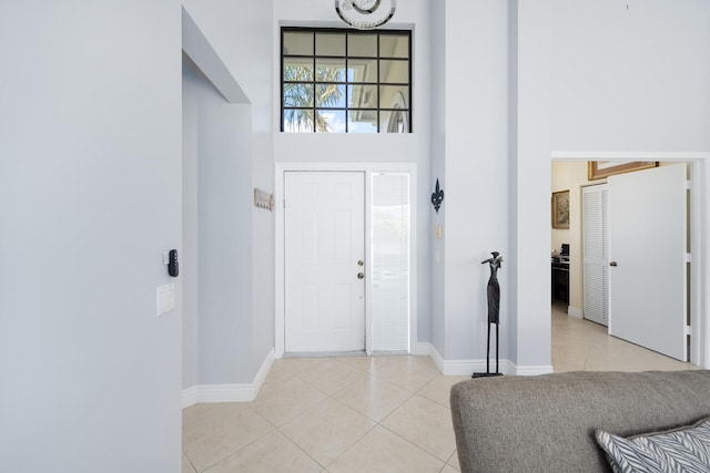 entrance foyer featuring baseboards, a high ceiling, and light tile patterned floors