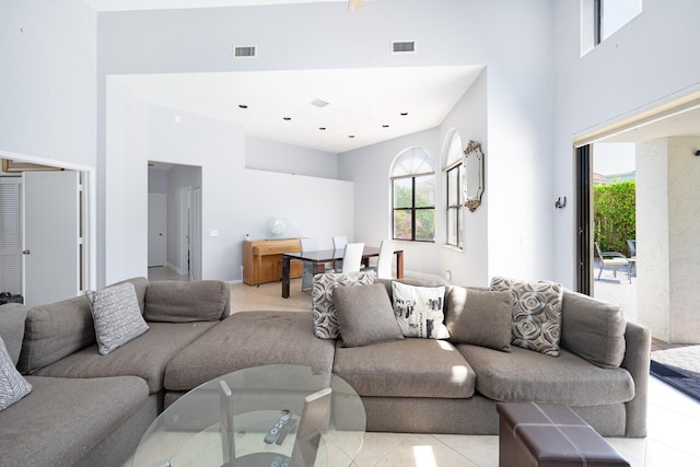 living area featuring a high ceiling, plenty of natural light, and visible vents