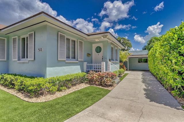 view of front of home featuring driveway, a front lawn, and stucco siding