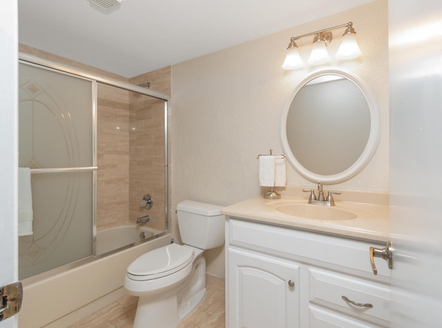 bathroom with shower / bath combination with glass door, vanity, and toilet