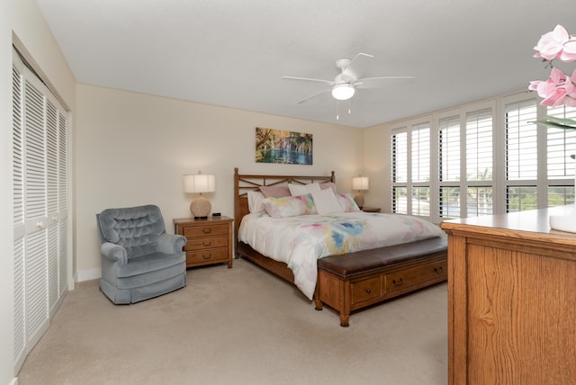 bedroom with a ceiling fan, a closet, and light colored carpet