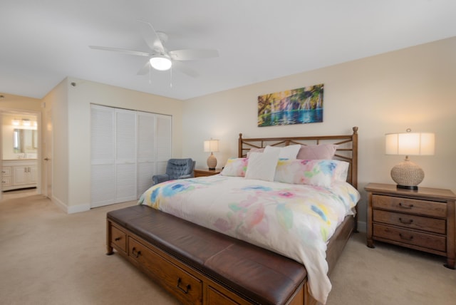 bedroom with a closet, light carpet, ceiling fan, ensuite bath, and baseboards