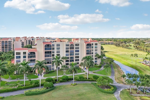 view of building exterior with view of golf course, a water view, and curved driveway