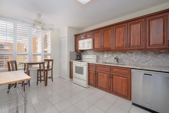 kitchen featuring light stone counters, light tile patterned floors, decorative backsplash, a sink, and white appliances