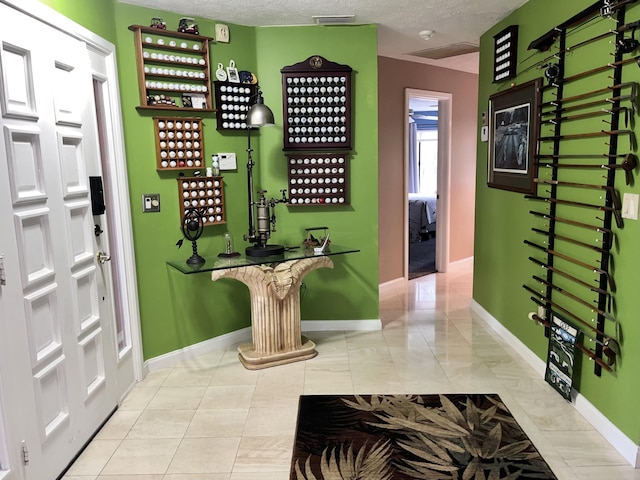 entrance foyer with baseboards, visible vents, and a textured ceiling