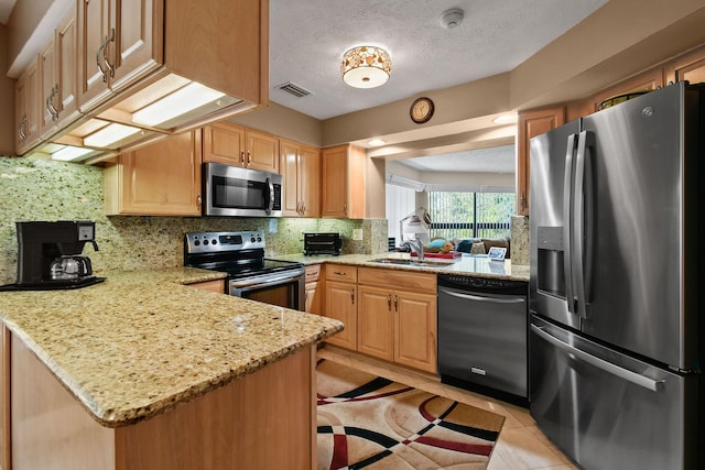 kitchen featuring visible vents, a sink, backsplash, stainless steel appliances, and a peninsula